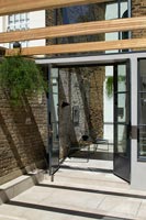 Open patio doors with view of black modern chairs inside extension 