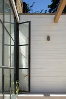 Black framed glass door to terrace against white painted exterior wall 