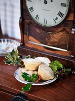 Mince pies next to antique clock on wooden sideboard 