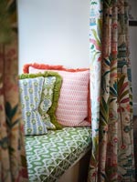 Patterned fabric covered cushions and curtains on window seat 
