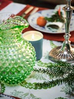 Detail of dining table with textured glass jug and silver candlestick 
