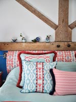 Blue and red patterned cushions and headboard in country bedroom 