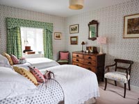 Patterned wallpaper, curtains and furnishings in eclectic country bedroom 