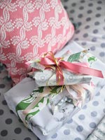 Wrapped gifts on bed next to patterned cushions 