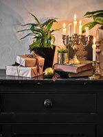 Candles and Christmas gifts on sideboard 