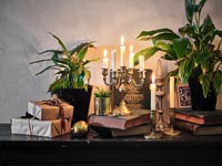 Candles and Christmas gifts on sideboard 