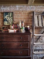 Wooden chest of drawers next to exposed brickwork wall