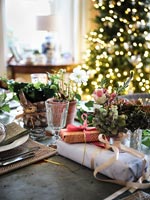 Christmas gifts on dining table with tree in background 