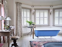 Freestanding roll-top bath in modern country bedroom 