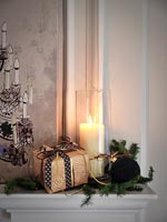 Christmas gift, decoration and lit candle on mantelpiece 