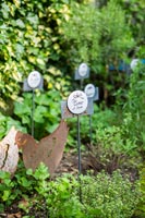 Decorative plant labels and chicken ornaments in herb garden 