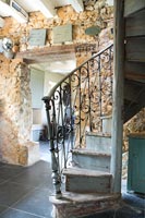 Spiral staircase and exposed stone wall in country hallway 