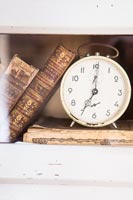 Detail of old alarm clock and leather bound books 