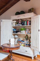 Old linen press used as storage cupboard for books and accessories 