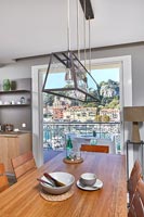 Dining area in modern coastal apartment with views of port through windows 