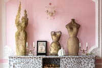 Golden sculptures against pink wall in eclectic living room 