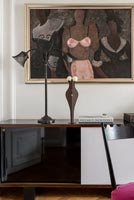 Modern artwork, sculpture and lamp on sideboard 