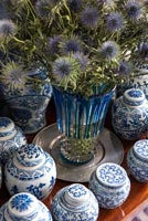 Flowers in vase surrounded by collection of blue and white china 