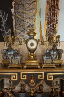 Gold and black artwork and antiques on ornate sideboard 