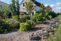 Country house and garden with log stepping stones along gravel pathway