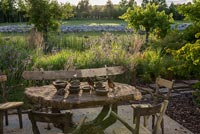 Rustic table and chairs on terrace overlooking country garden in summer 