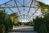 Huge metal structure over decked area with seating in large country garden