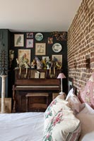 Small piano covered in ornaments in eclectic bedroom 