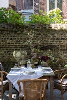 Garden table laid for lunch in walled courtyard garden 