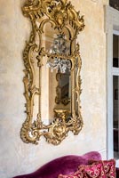 Detail of classic gilded mirror on bare plaster wall 