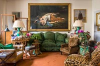Large classic painting above green velvet sofa in eclectic living room 