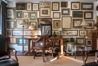Feature wall display of framed paintings in country study 