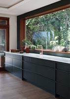 Modern kitchen with large window above sink and worktop 