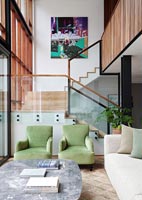 Green armchairs in modern living room with view of staircase 