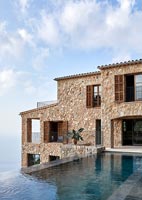 Stone coastal house exterior with infinity pool and sea views 