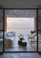 Day bed and armchairs on covered terrace overlooking the sea at sunset 