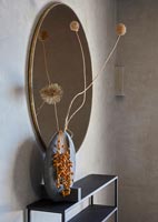 Detail of oval mirror and vase of dried flowers 