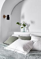 Pillows and cushions on bed with arched alcove and built-in headboard 