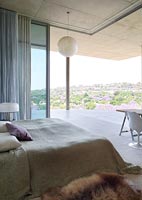 Modern bedroom with scenic views through open sliding doors to terrace 