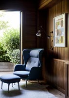 Armchair and footstool next to patio doors in modern living room 