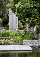 Stone retaining wall around water feature in modern country garden