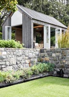 Stone retaining wall around water feature in modern country garden