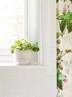 House plant on bathroom windowsill next to floral shower curtain 