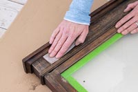 Woman rubbing down old wooden frame - memories notice board 