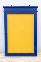 Painted blue wooden frame with yellow fabric covered corkboard