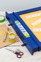 Painting stencil letters on memories notice board 