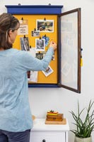 Woman pinning item into blue and yellow notice board 