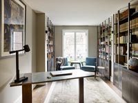 Desk and chair in study with armchairs and bookshelves 