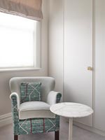 Patterned armchair and small side table in dressing room 