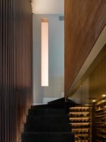 View up illuminated staircase between stone and wooden slatted walls 