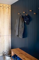 Wooden bench seat and coat hooks in modern country hallway 